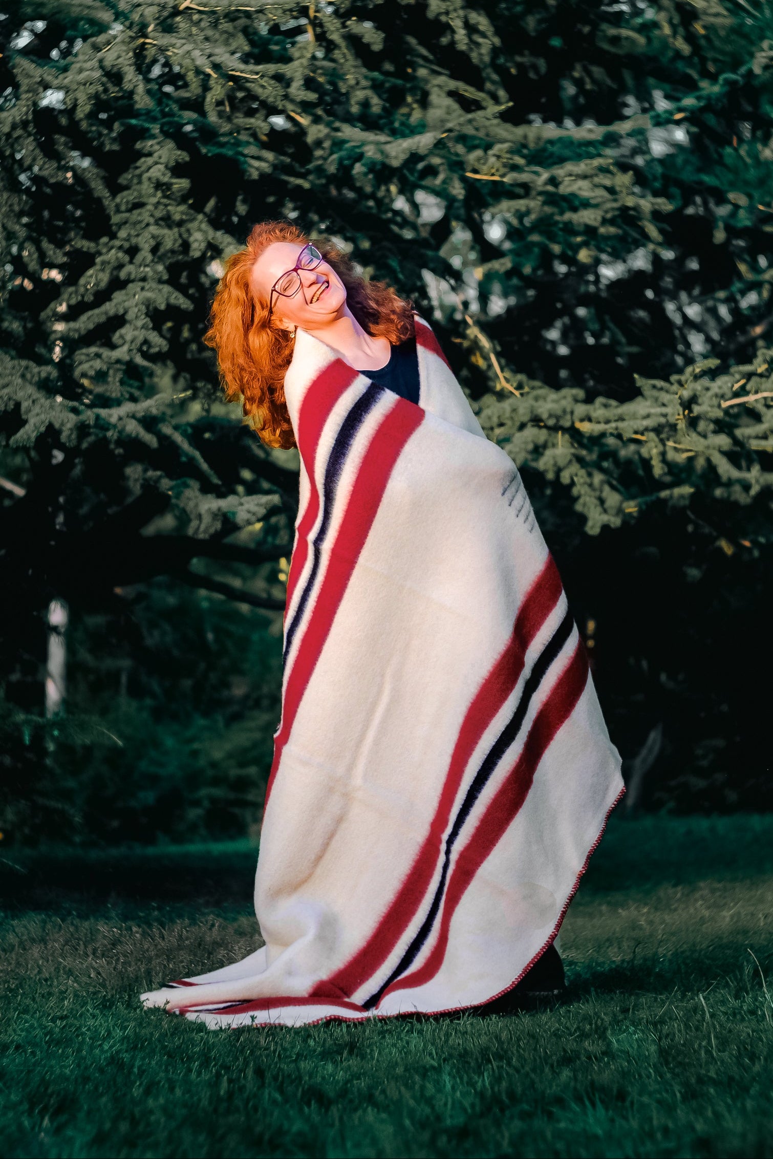 Woman wrapped in a thick warm ivory Blanket with red and black stripes, made of handwoven pure wool