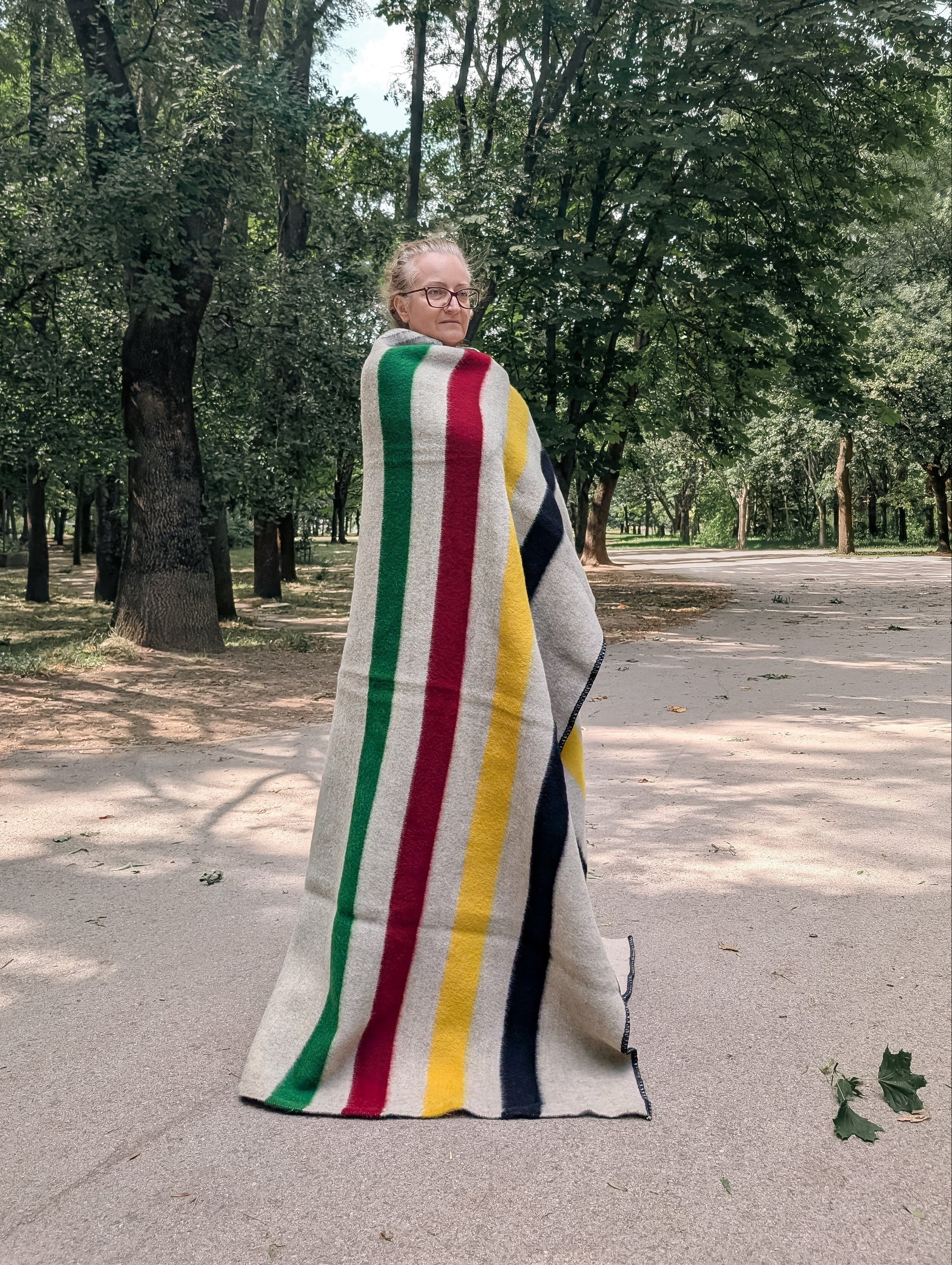 Woman wrapped in a heirloom heritage  blanket with stripes, inspired from the first nations' and Canadian legacy. 