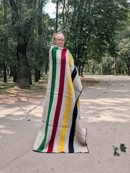 Woman wrapped in a heirloom heritage  blanket with stripes, inspired from the first nations' and Canadian legacy. 