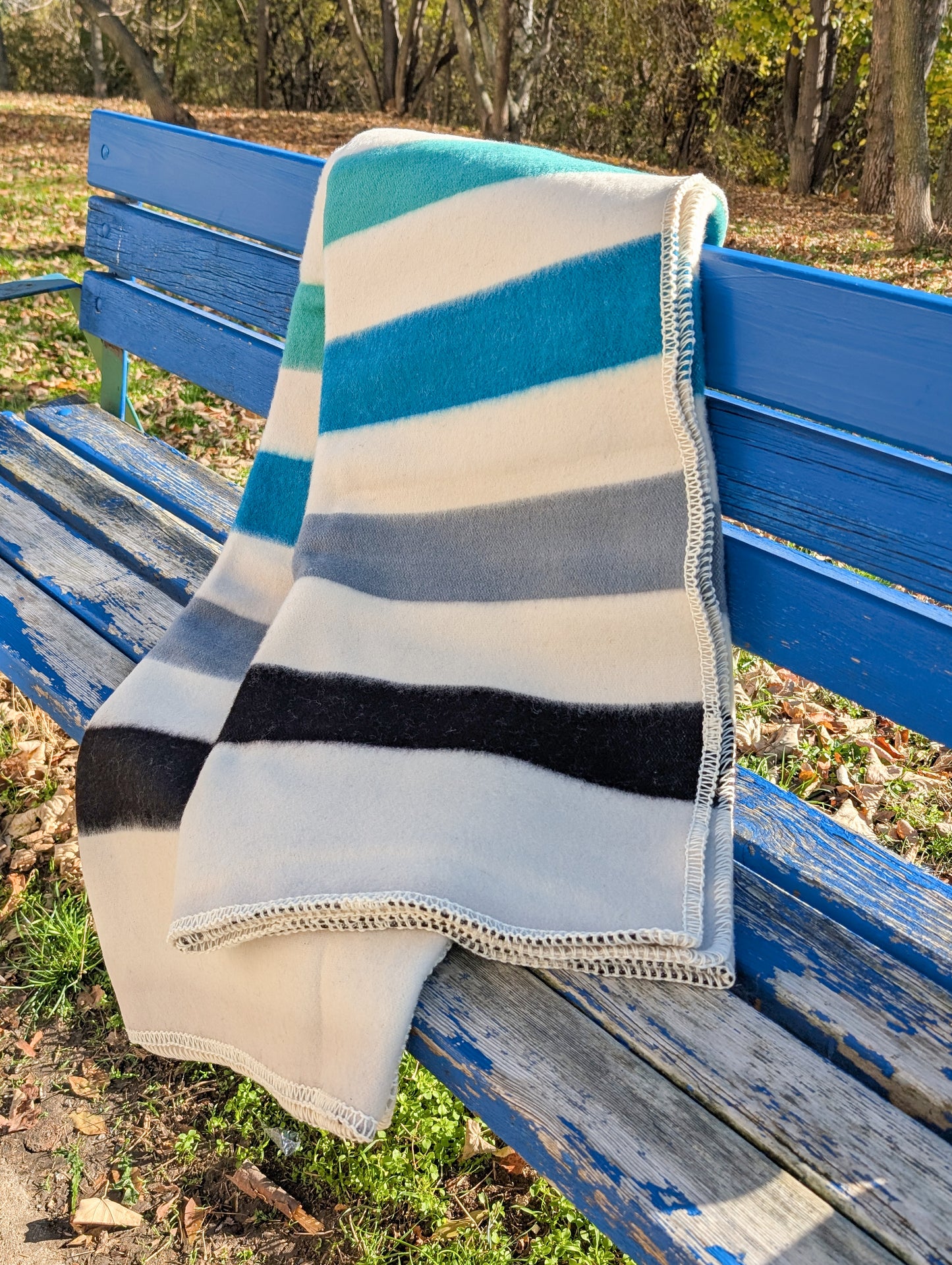 Traditional handmade striped blanket draped over a blue bench in an outdoor setting