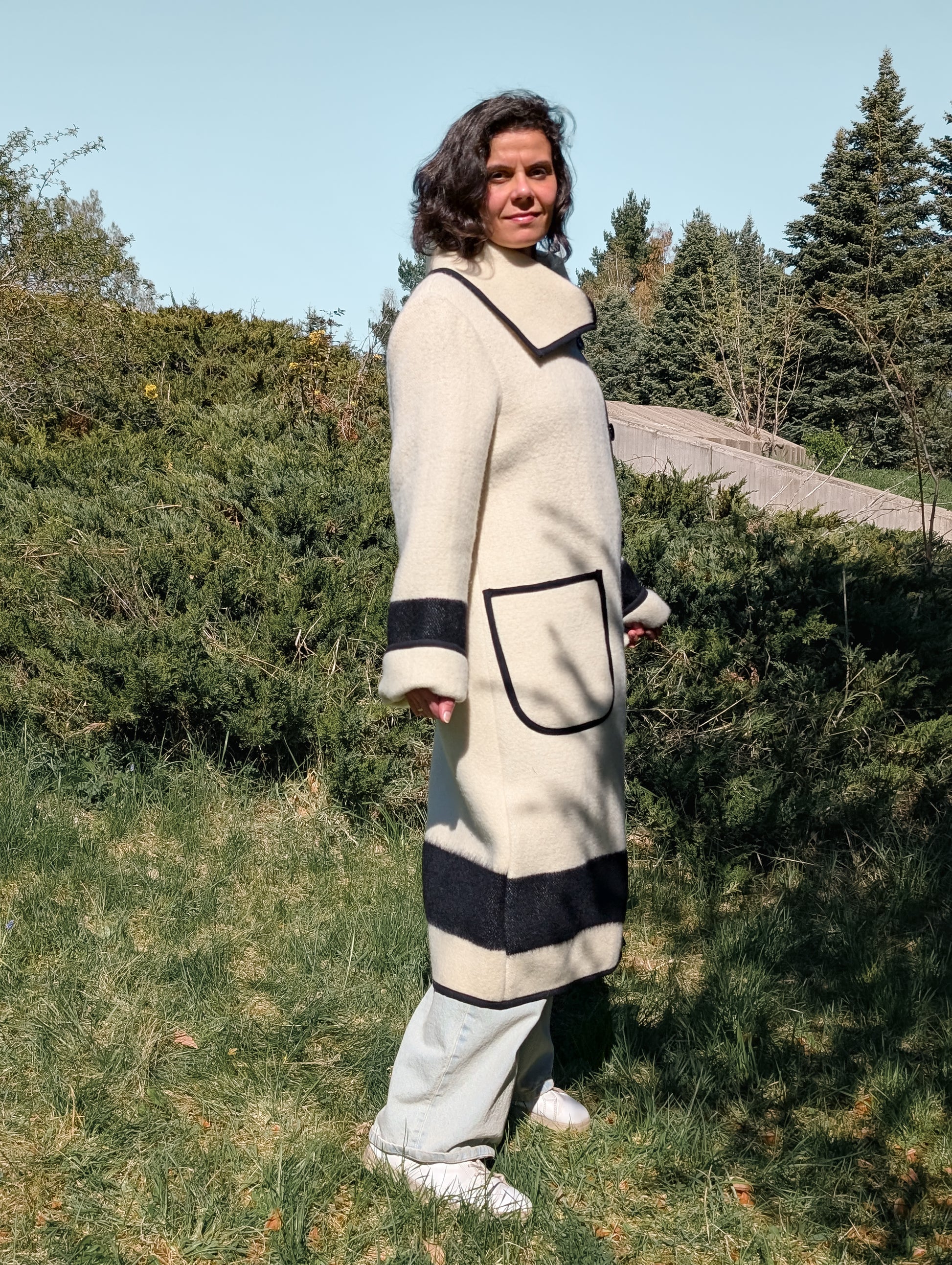 Woman wearing a long cream collar coat with black stripes, made from authentic luxurious wool blanket.