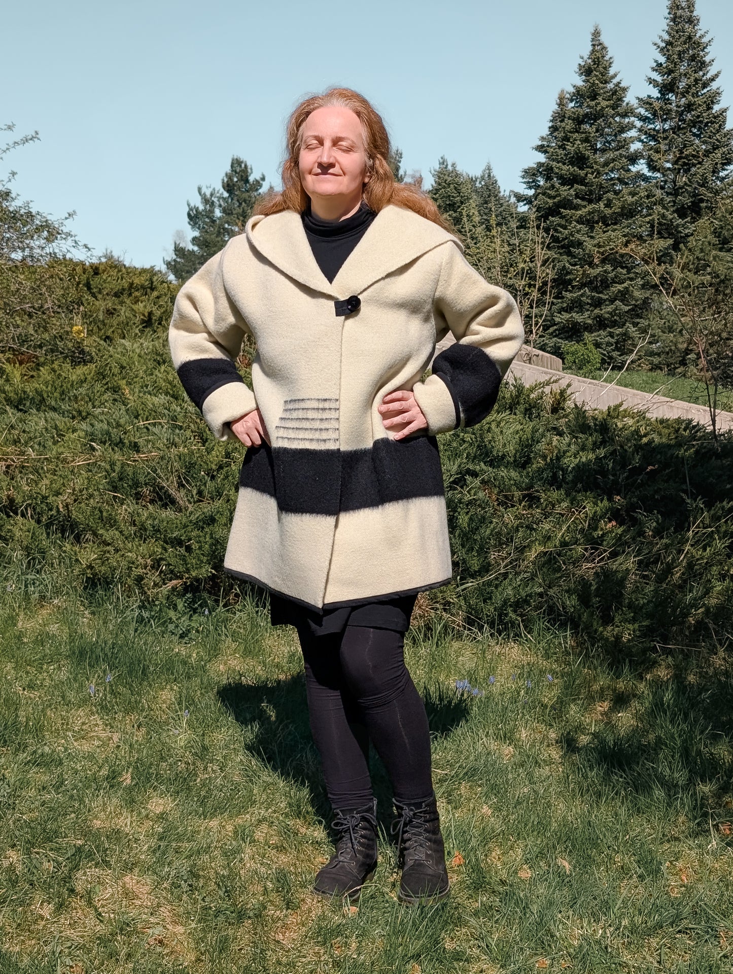Woman wearing wool swing coat repurposed from sustainable wool blanket, in ivory color, black stripes and a wide capote.