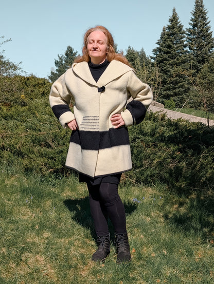 Woman wearing wool swing coat repurposed from sustainable wool blanket, in ivory color, black stripes and a wide capote.