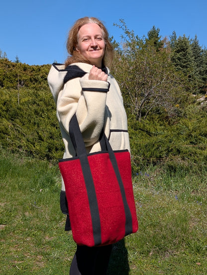 Woman dressed in bohemian style with an offwhite hoodie and a matching shopper bag in bold red, both made from authentic handmade wool blankets.