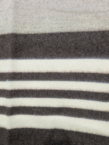 A detail of a minimalist gray wool blanket with beige and brown stripes. Undyed virgin sheep's wool handmade product.