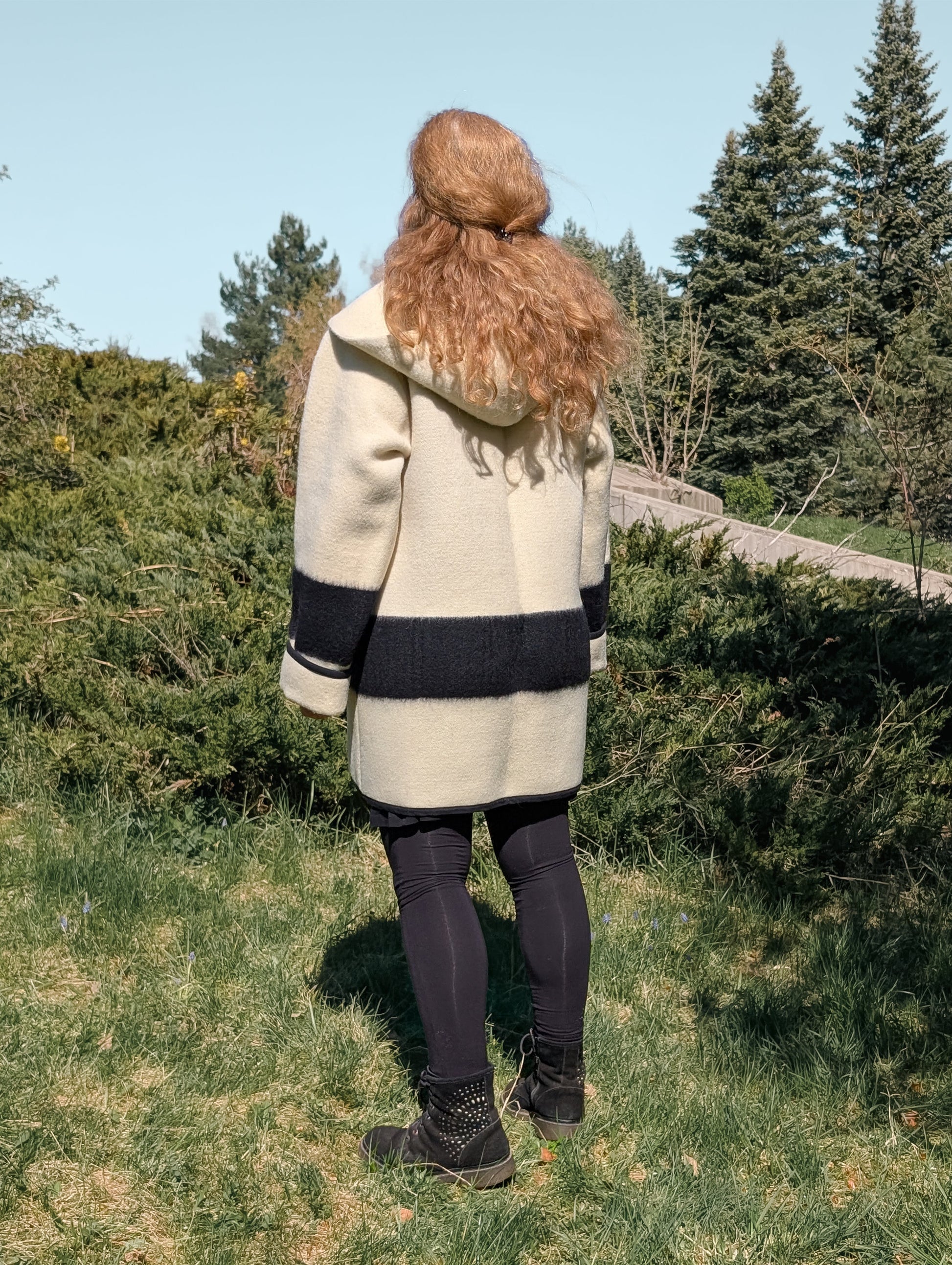 Woman posing backwards with a slow fashion native american style capote coat or swing coat