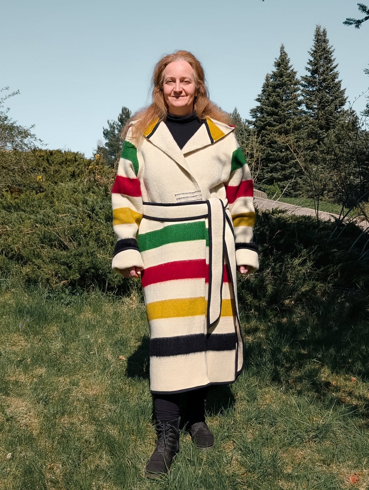 A woman wearing a long custom made capote coat upcycled from a sustainable natural sheep wool blanket