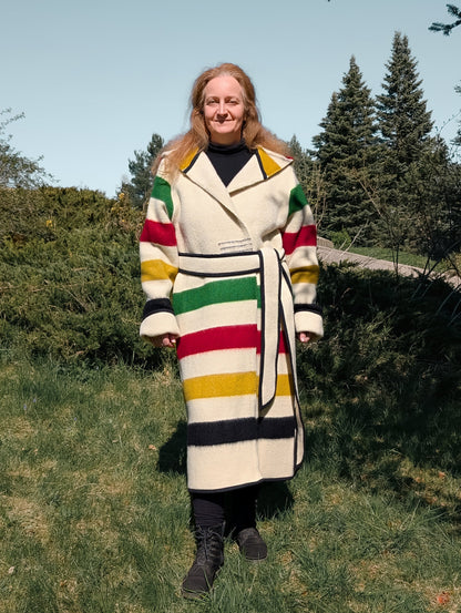 A woman wearing a long custom made capote coat upcycled from a sustainable natural sheep wool blanket