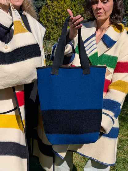 Woman holding a deep blue blanket tote bag with a statement black stripe