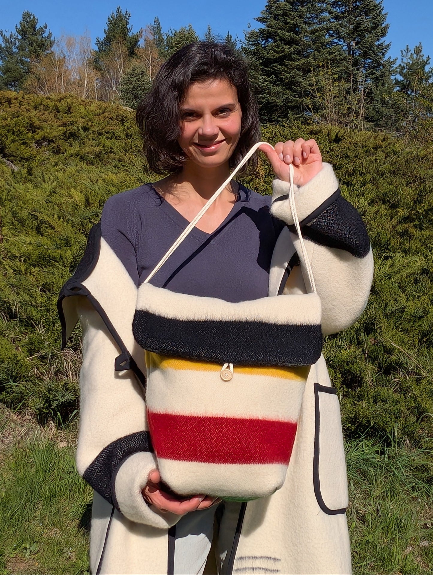 Woman holding a colorful stripes tote bag made of recycledvirgin wool blanket.