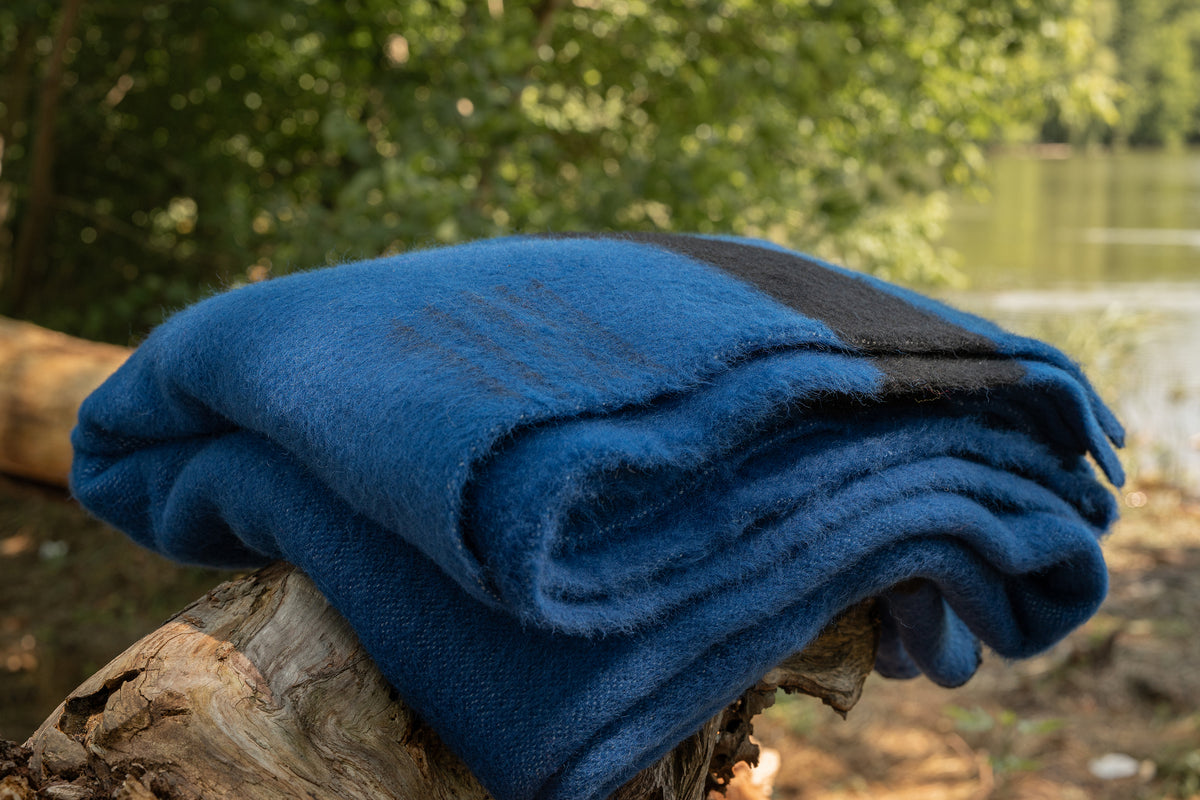 Large blue picnic blanket with iconic black stripes, handcrafted traditionally with natural wool using a slow handmade process.