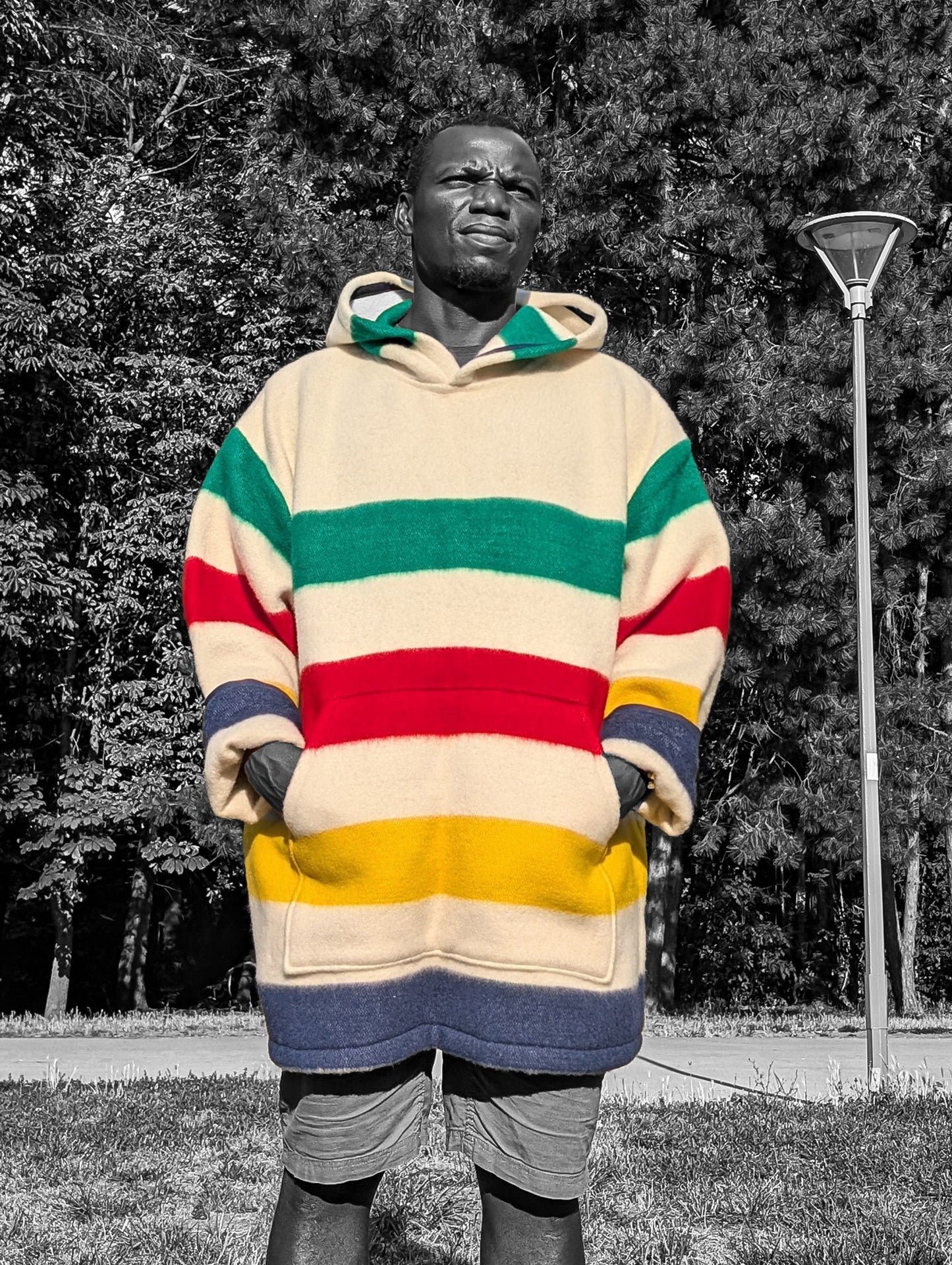 Man wearing a unisex multi stripe blanket hoodie anorak with ivory base and colorfuls stripes, recucled from an organic wool blanket.