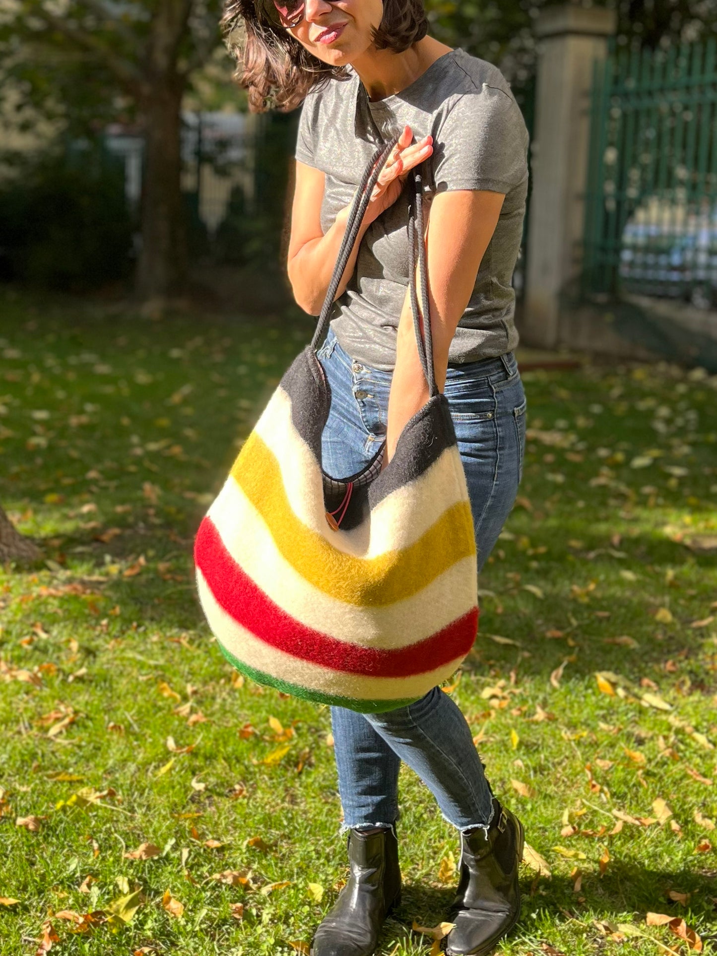 Woman holding a modern everyday boho bag with iconic statement stripes in various colors. The bag is recycled from a luxurious authentic handwoven wool blanket. 