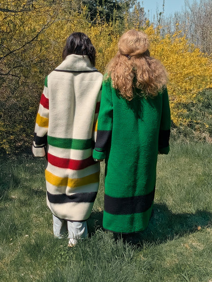 Two women wearing long, striped dusters or duster coats in bold traditional colors with iconic ethnic stripes. 