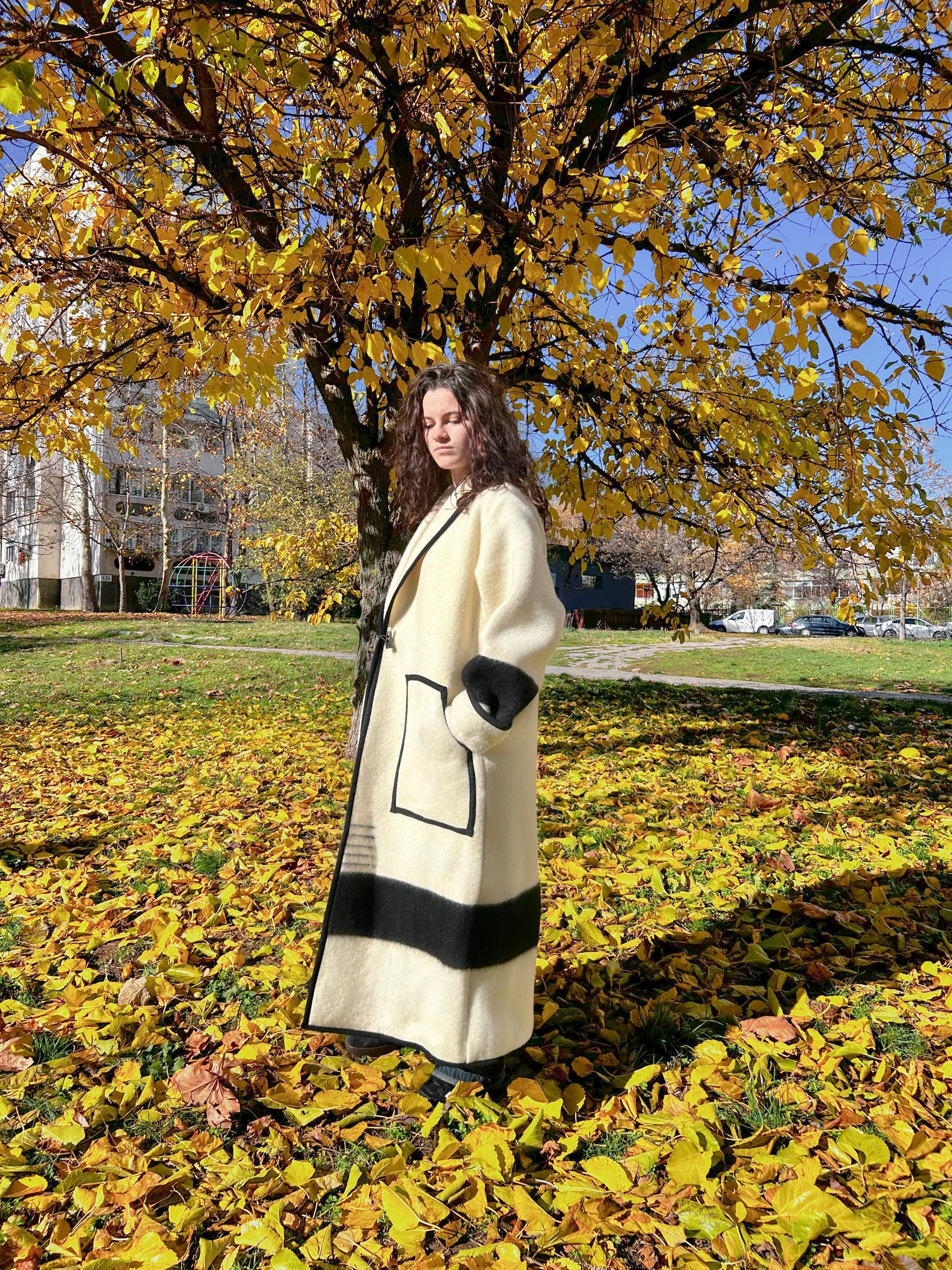 Woman in a Bohemian coatwith ivory base and wide black stripes upcycled from a white blanket.