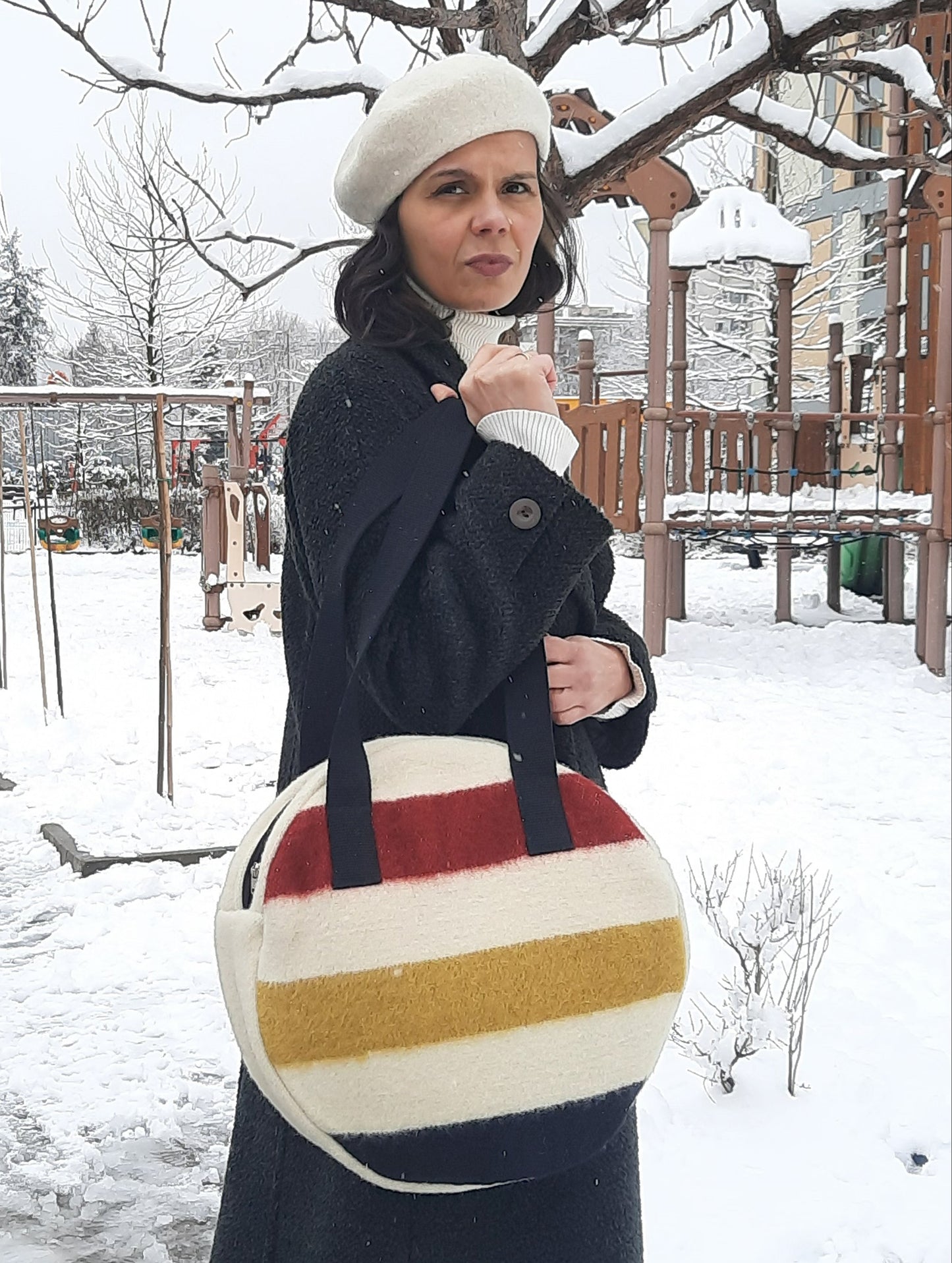 woman holding an iconic round shopping bag, made of pure wool stripe blanket.