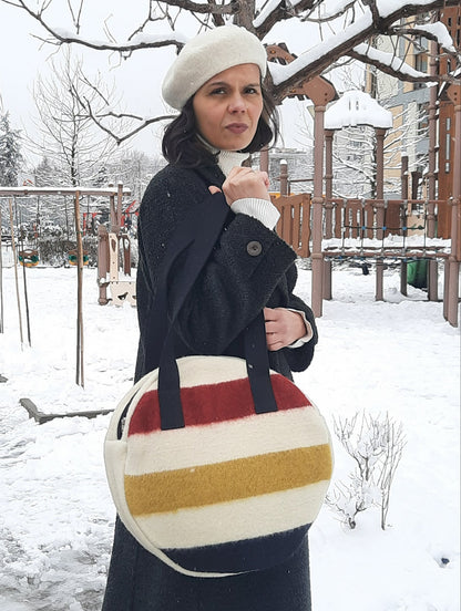 woman holding an iconic round shopping bag, made of pure wool stripe blanket.
