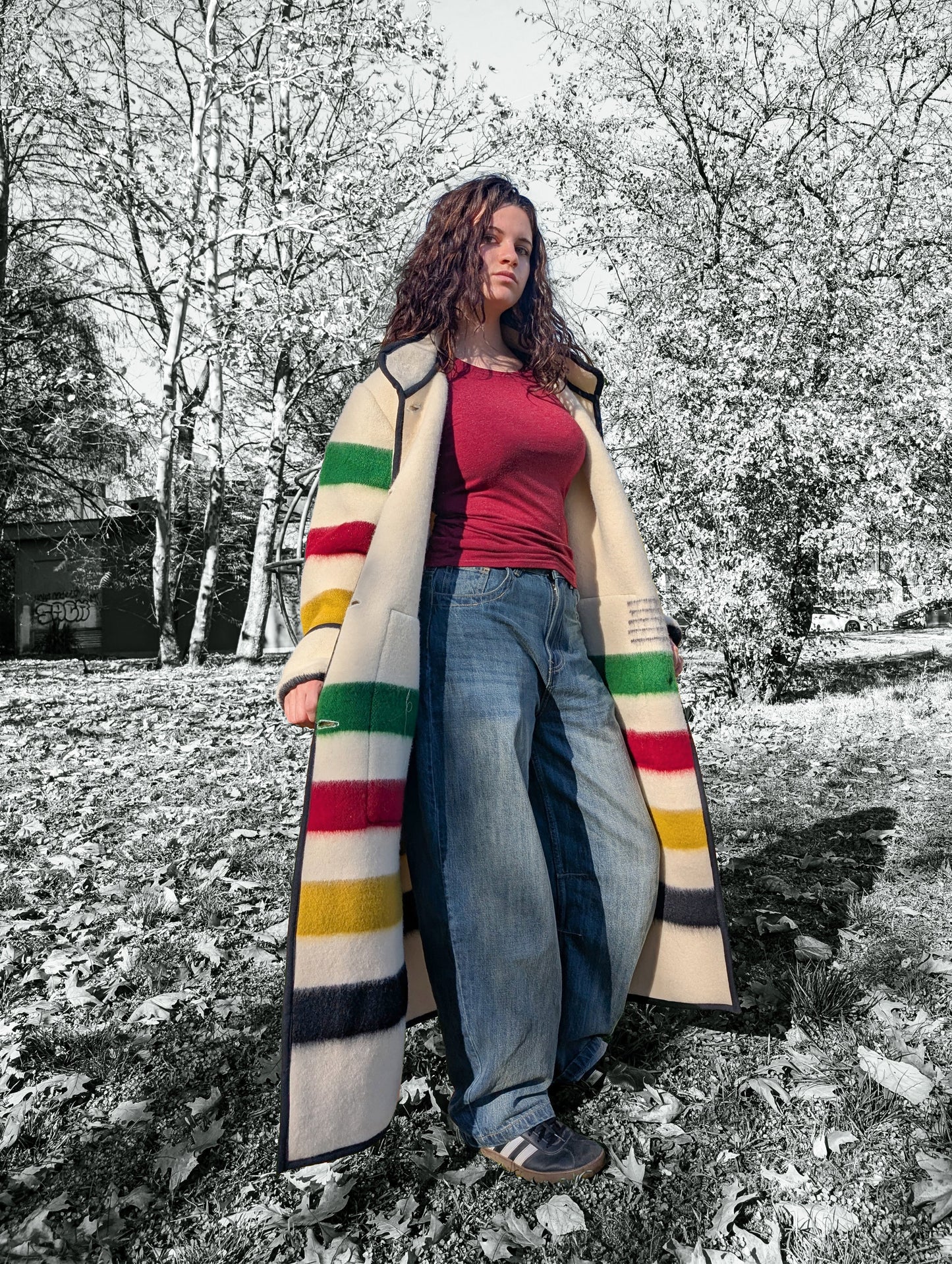 A girl wearing oversized duster coat with stand collar, two front pockets and single breasted. The background is a park setting