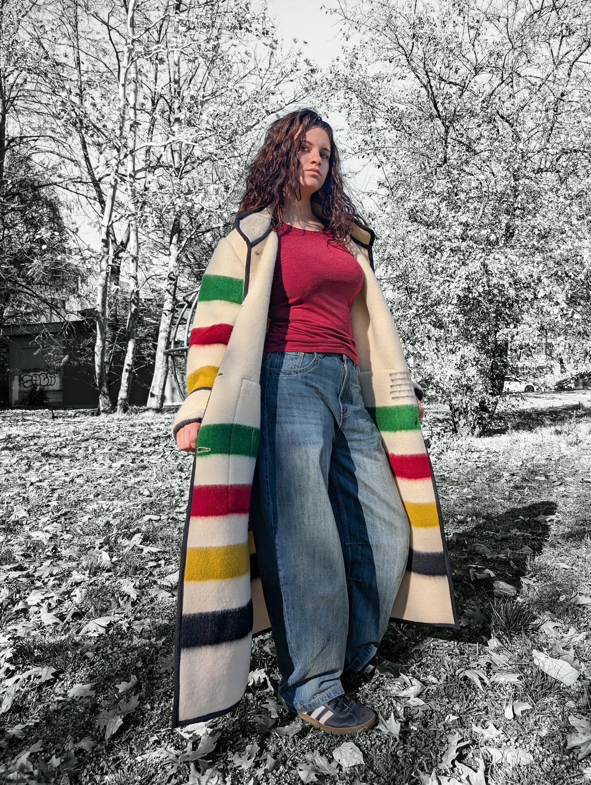 A girl wearing oversized duster coat with stand collar, two front pockets and single breasted. The background is a park setting