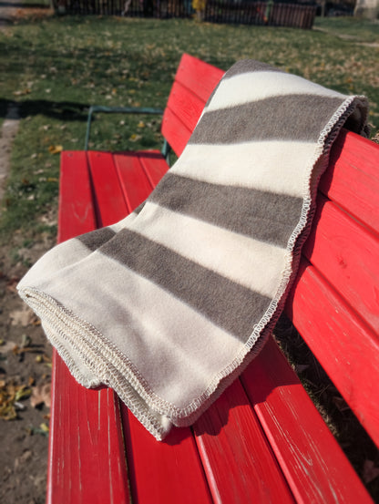 Beautiful cozy undyed wool blanket with natural stripes draped over a red bench, perfect for minimalist decor and camping.