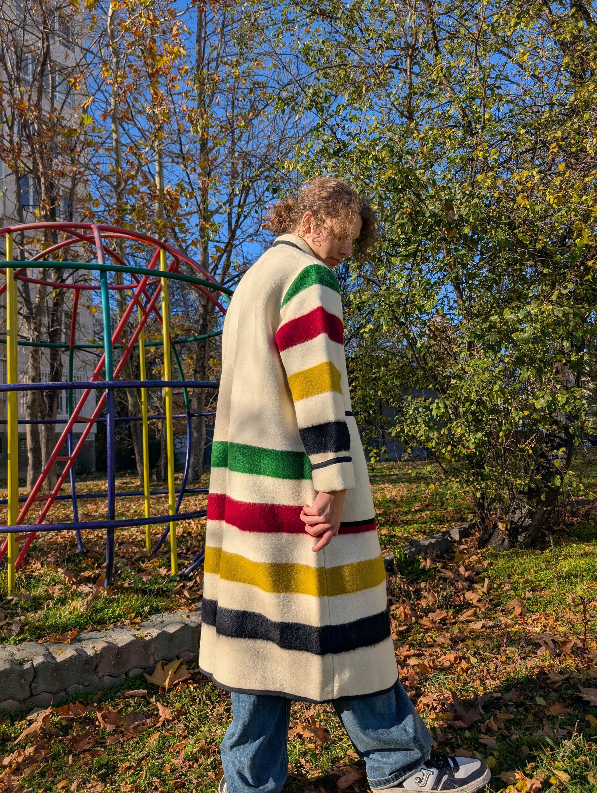 Young man wearing a long shawl collar coat upcycled from a wool blanket. Off-white base.