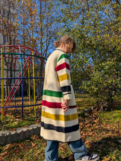 Young man wearing a long shawl collar coat upcycled from a wool blanket. Off-white base.