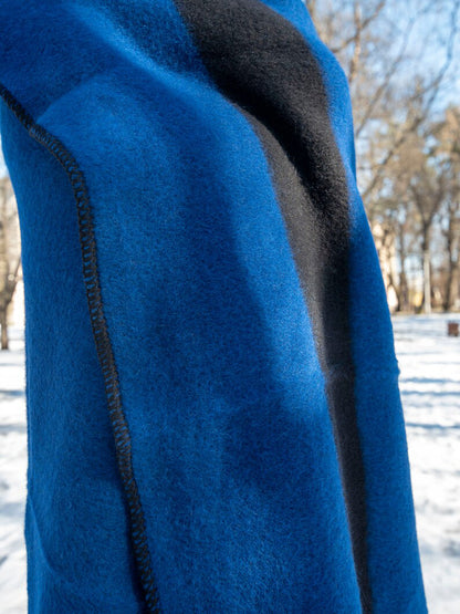 Close-up of a modern blue pure wool blanket throw with black line in a snowy outdoor setting