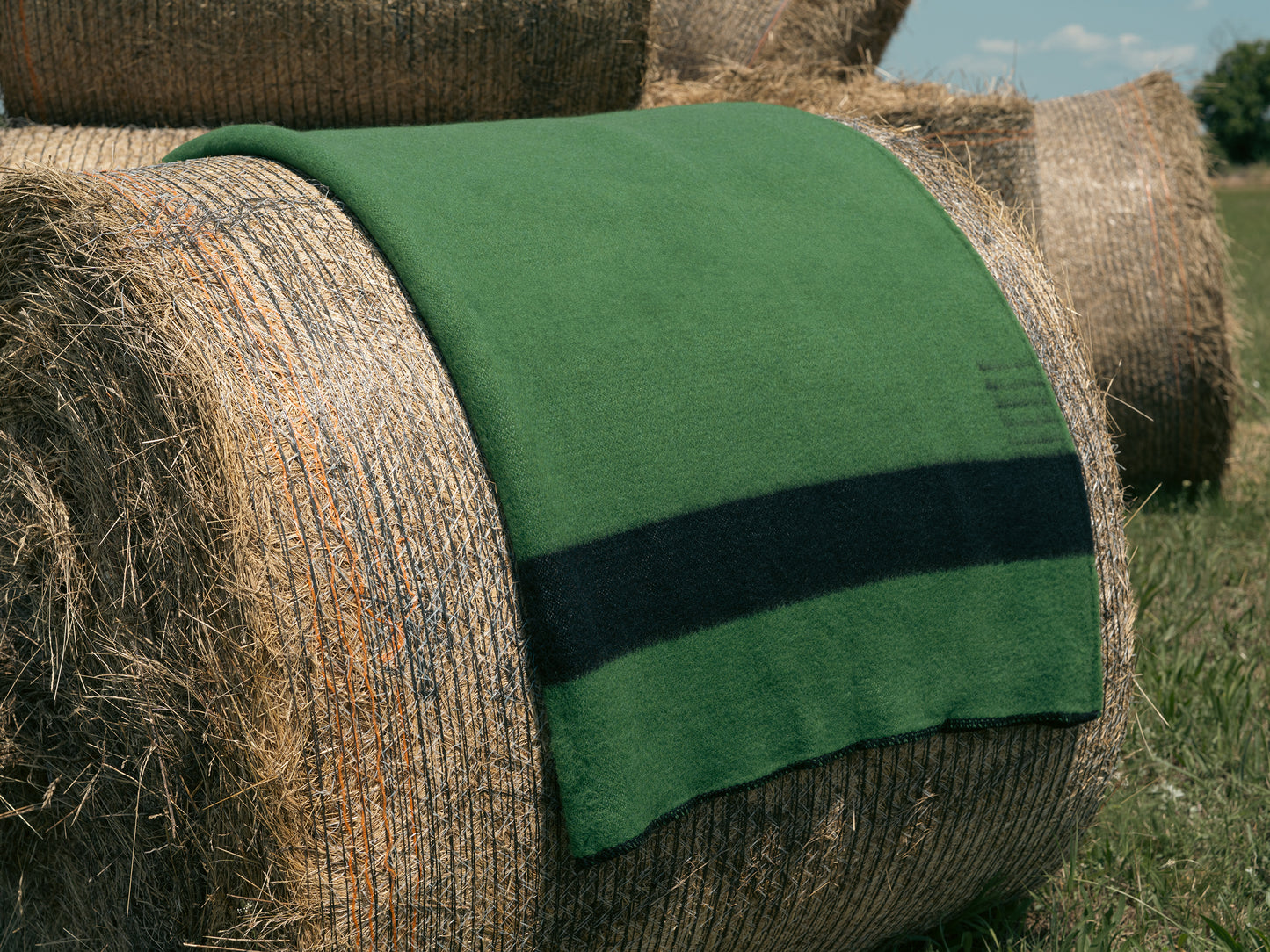 Hay bale with a green canadiana blanket on top in an outdoor setting