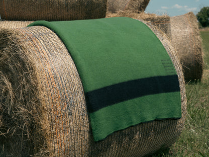 Hay bale with a green canadiana blanket on top in an outdoor setting