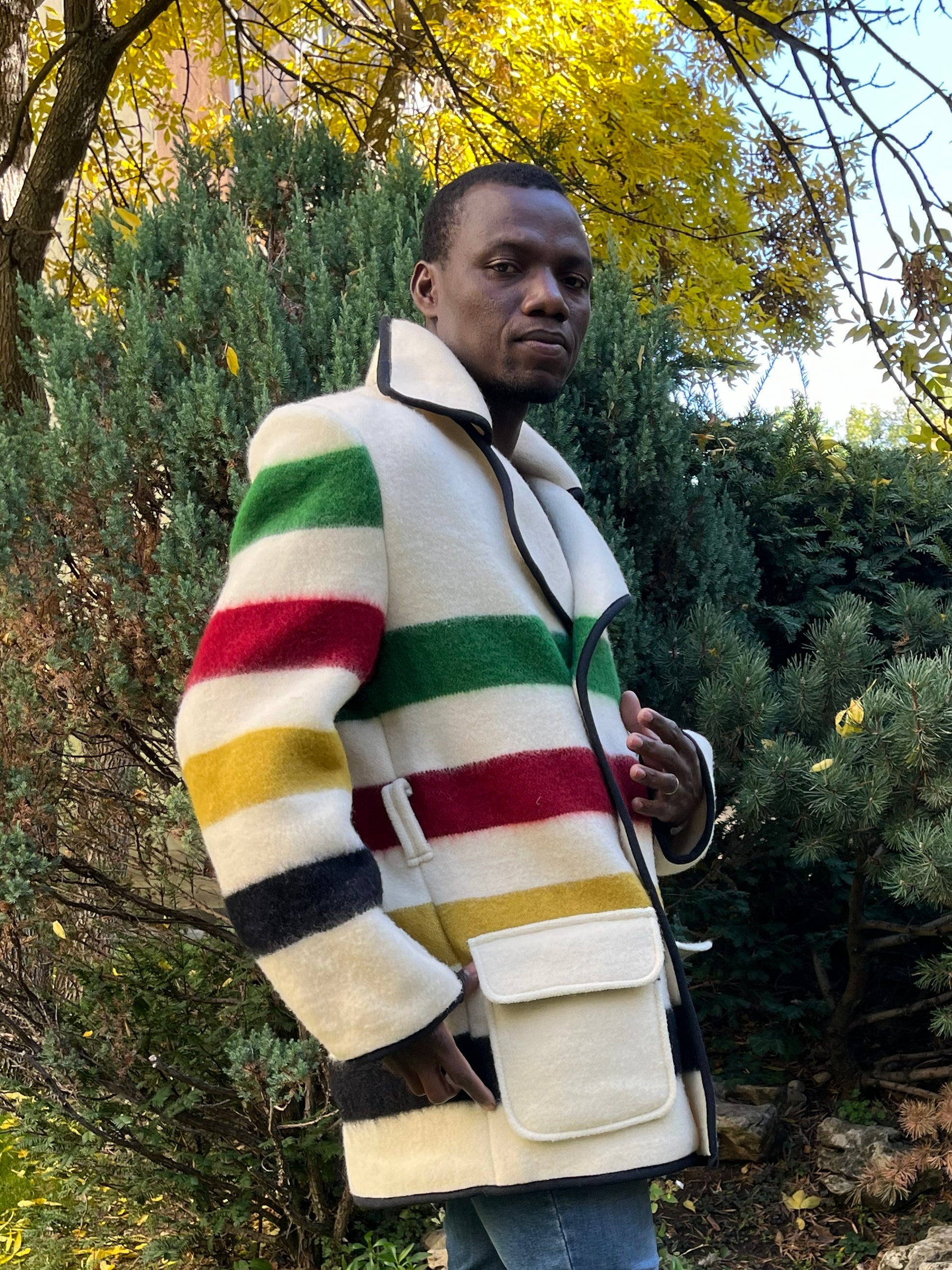 Man wearing a cool blanket coat with multicolor stripes, made from a new recicled pure wool blanket.