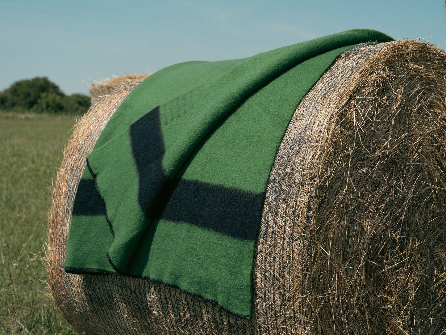 Green pioneer blanket on a hay bale in an open field