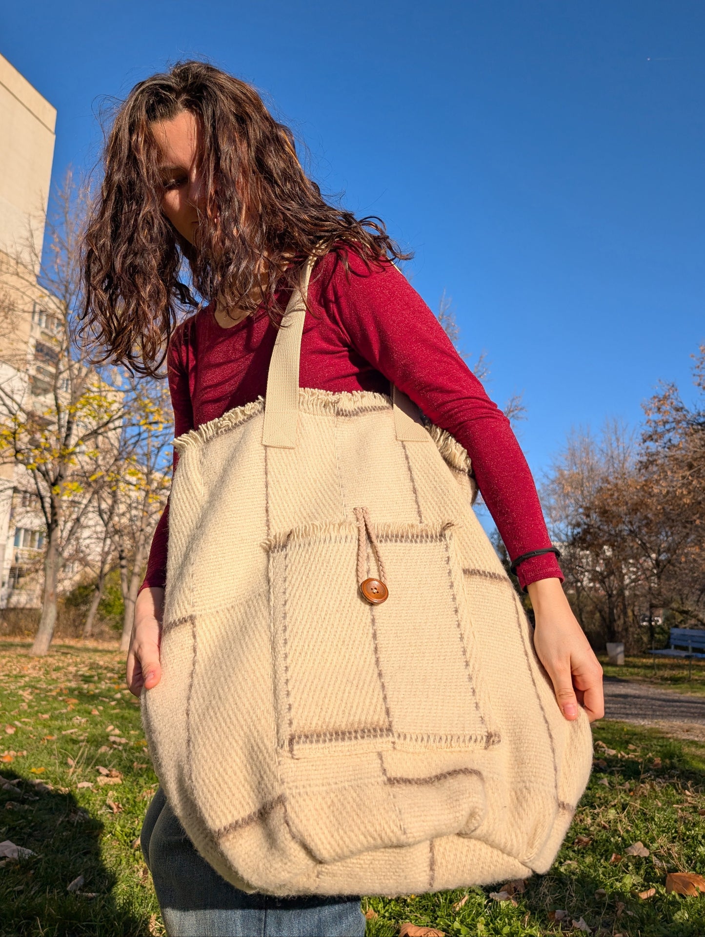 Young girl holding an undyed beige shopper bag upcycled from all natural wool minimalistic blanket.