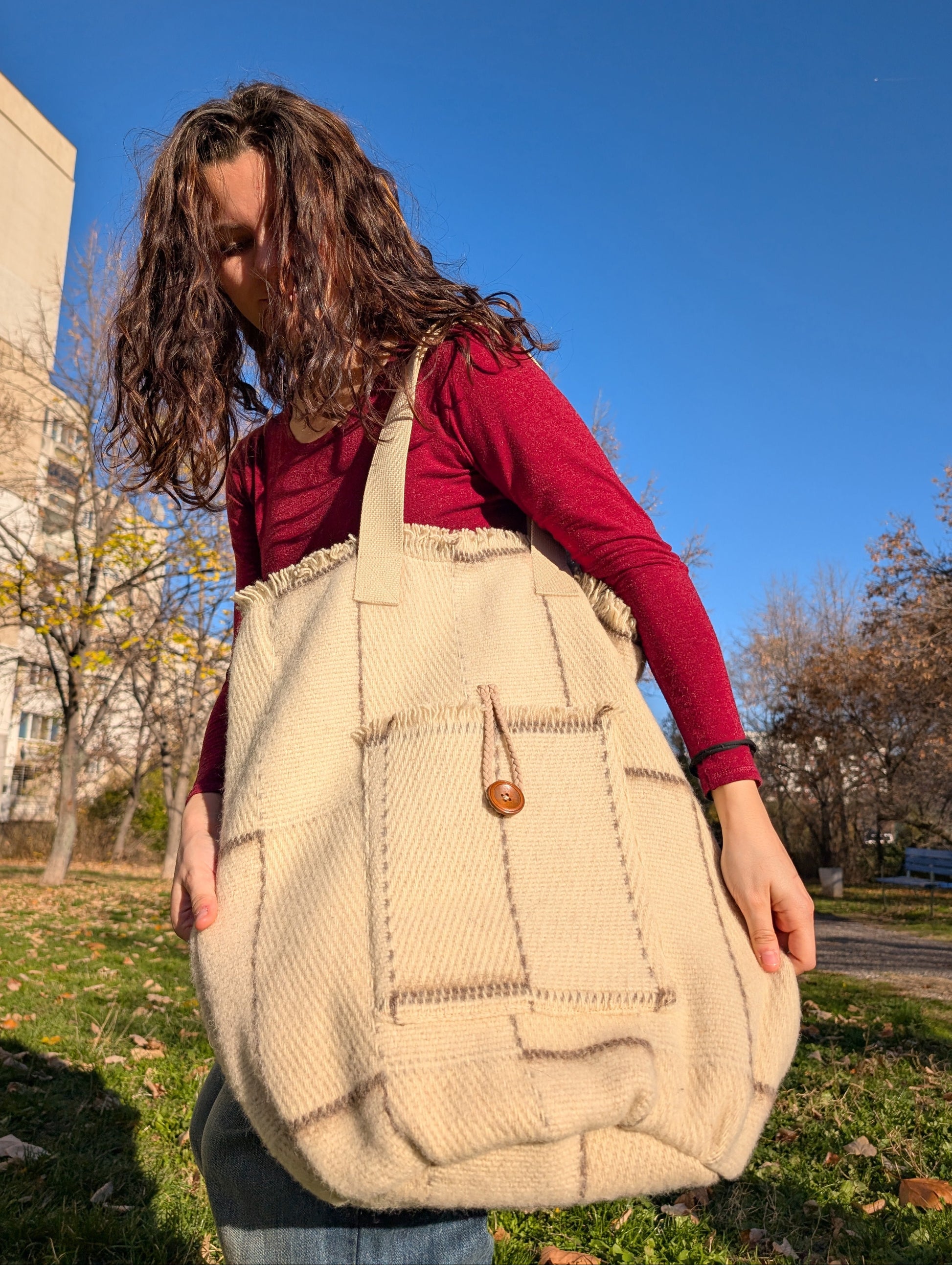 Young girl holding an undyed beige shopper bag upcycled from all natural wool minimalistic blanket.