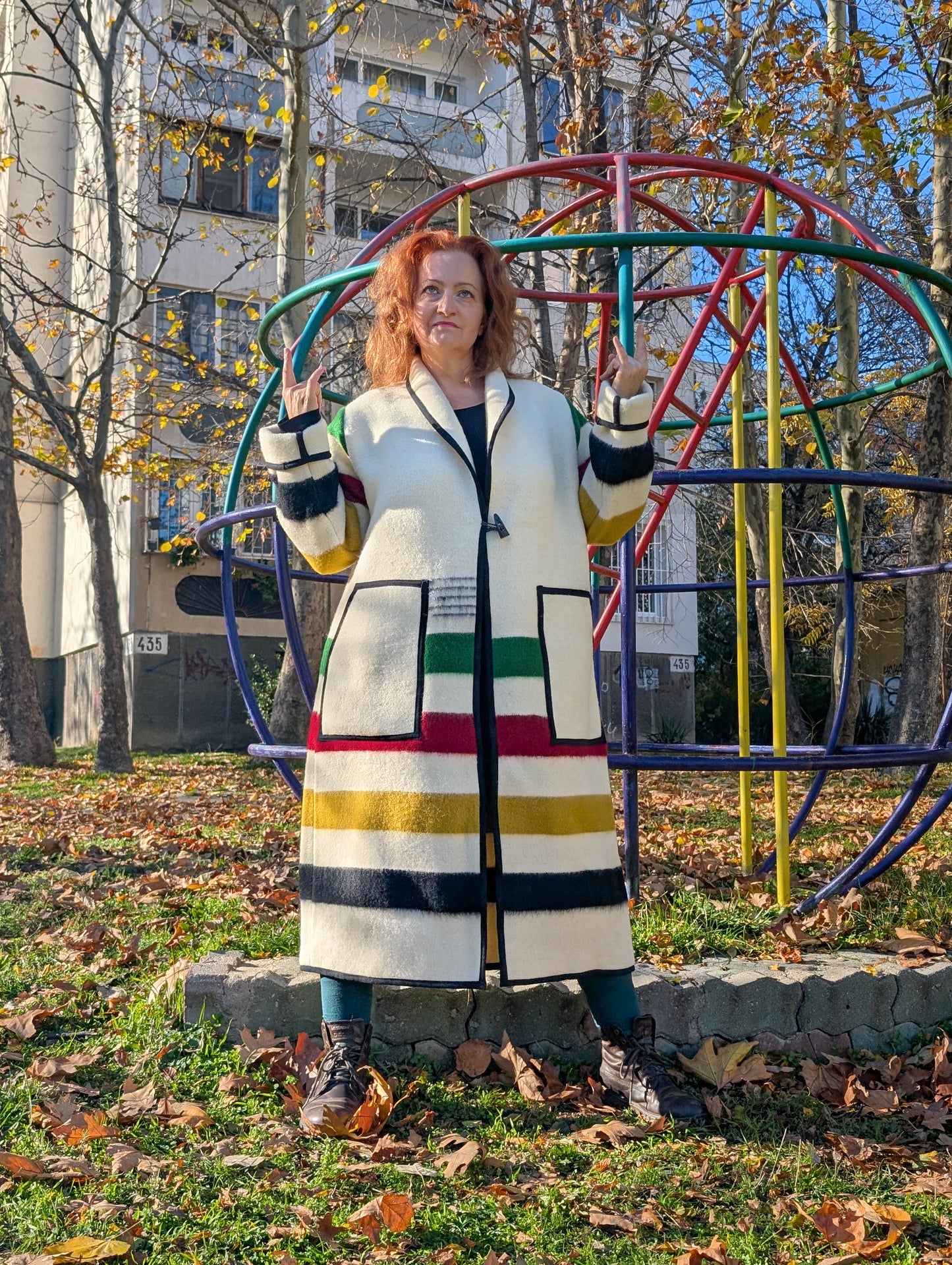 A woman posing with a loose long handmade cardigan coat, made from traditionally woven stripe blanket