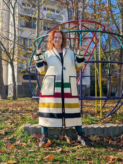 A woman posing with a loose long handmade cardigan coat, made from traditionally woven stripe blanket