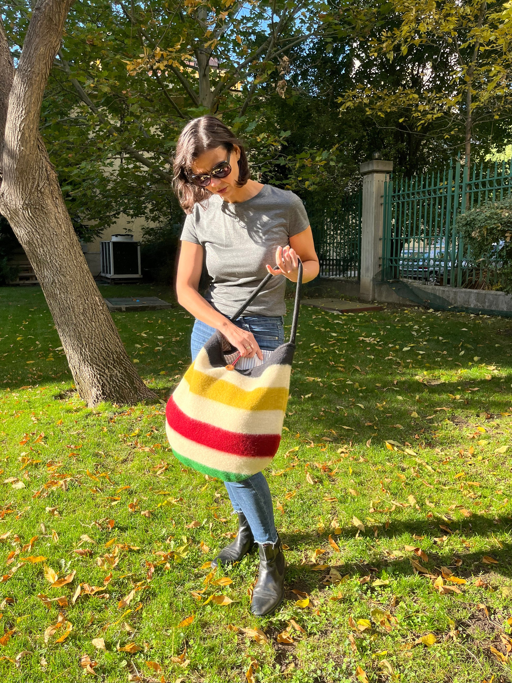 Woman holding a modern boho tote bag with colorful stripes made of sustainable wool blanket leftovers.