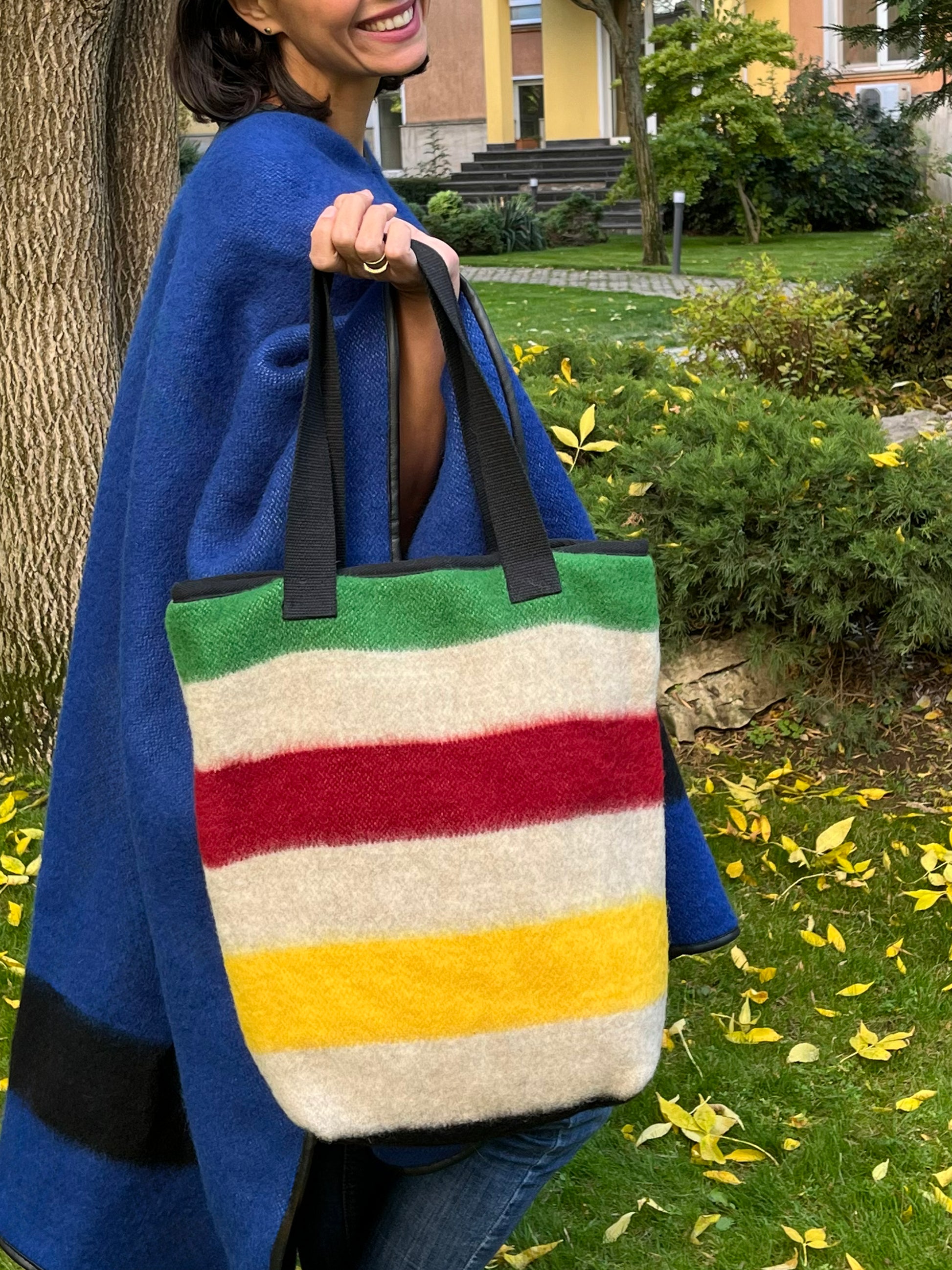 Person holding a modern minimalistic shopper bag in boho style with indigenous stripe pattern, recycled from locally handwoven natural wool blanket cuts.