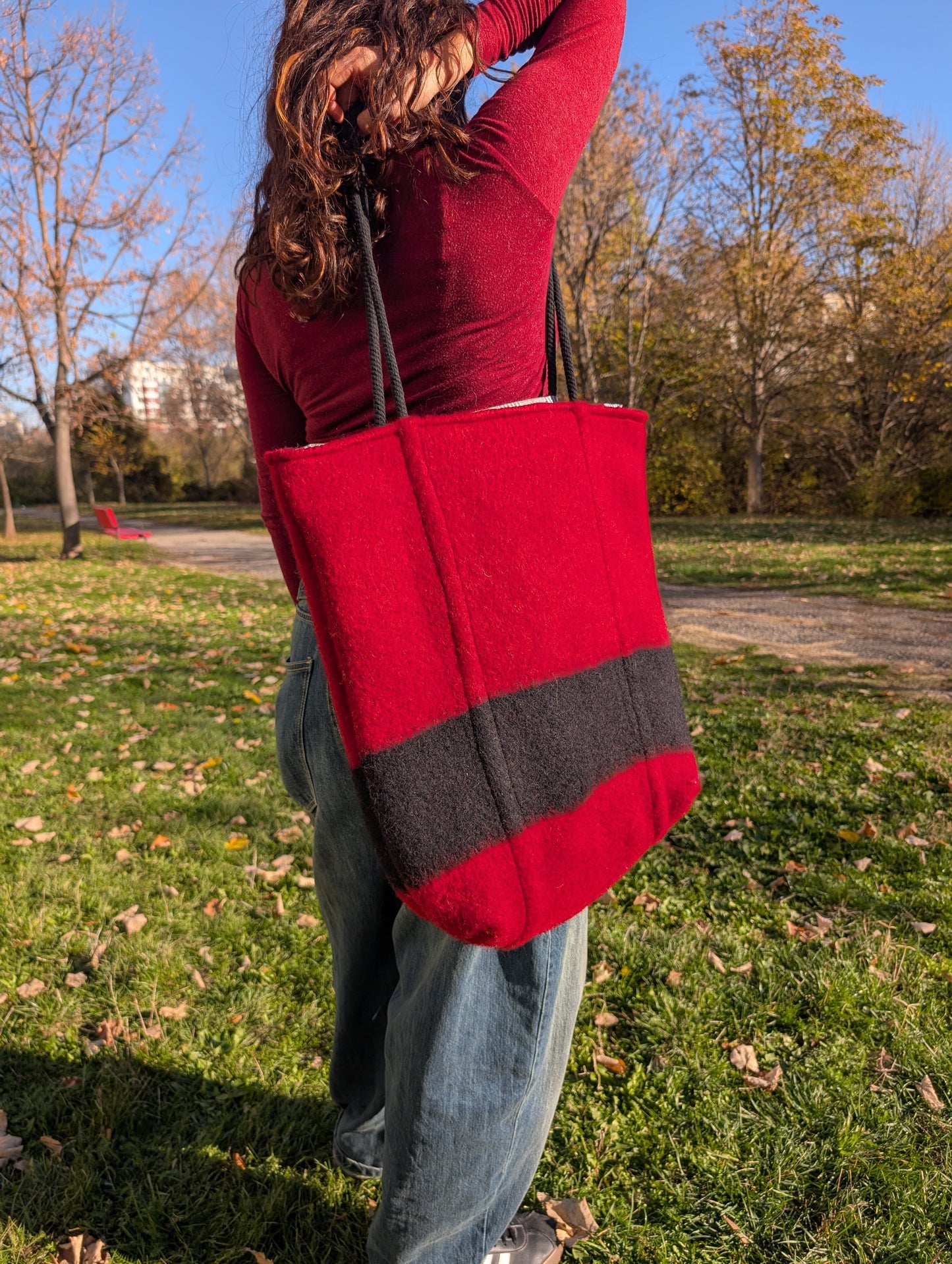 Woman wearing an iconic looking red woolen bag, upcycled from authentic handwoven wool blanket.  Artistic locally crafted item in red with black elements.