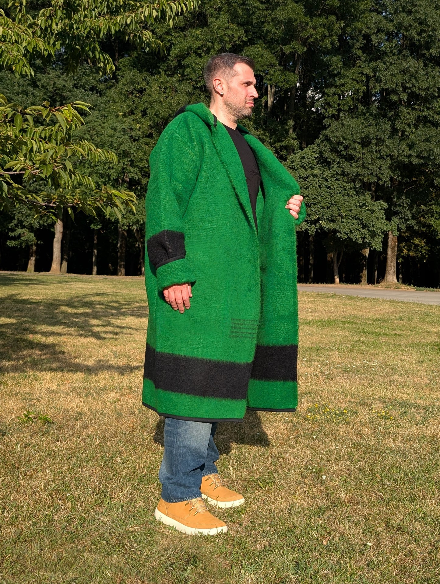 Man wearing a green blanket coat with black stripes made from repurposed authentic wool blanket.