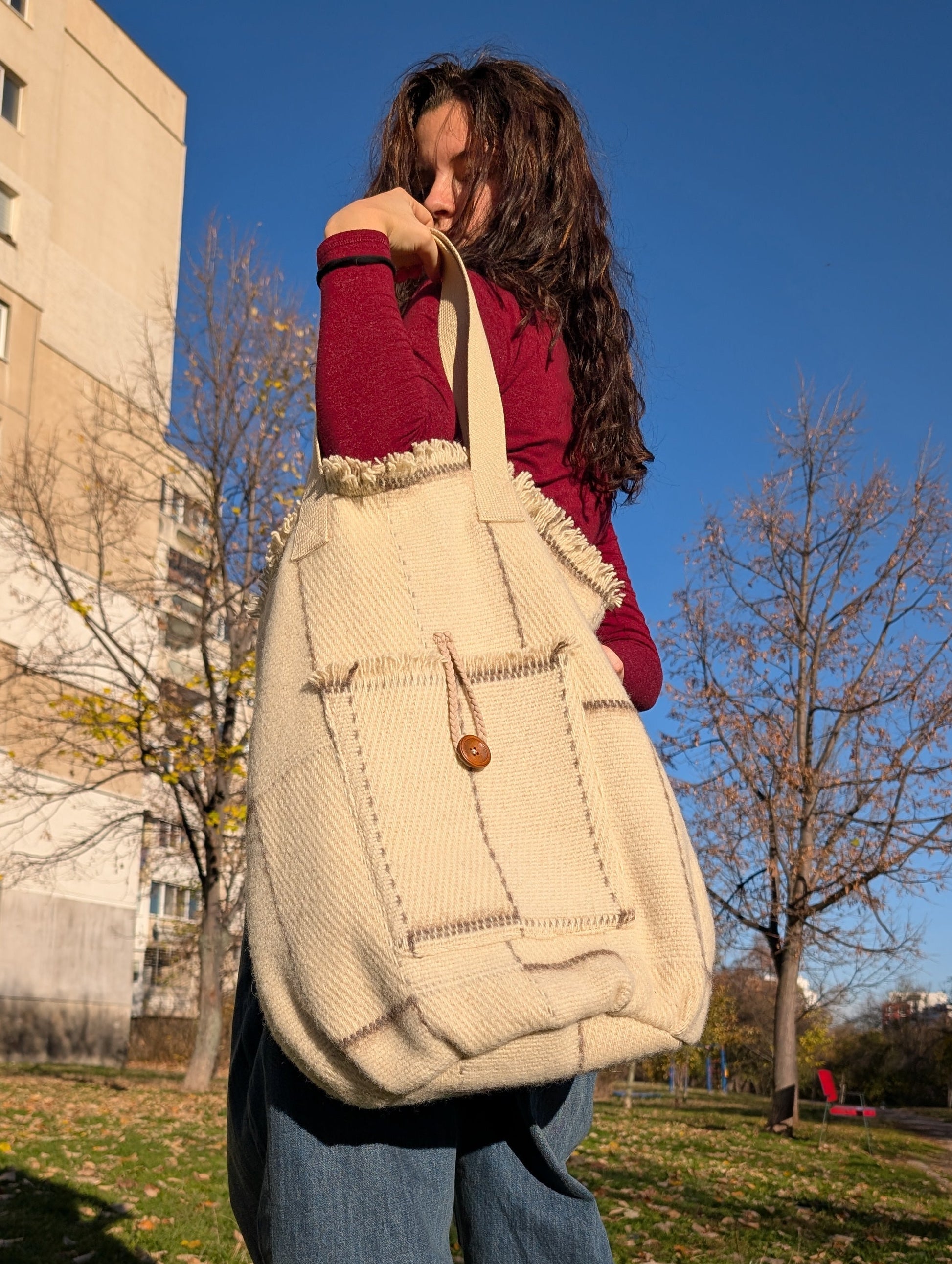 A young woman holding a natural boho style urban shopper bag, suitable for loose-fit style, urban, park and everyday walks.