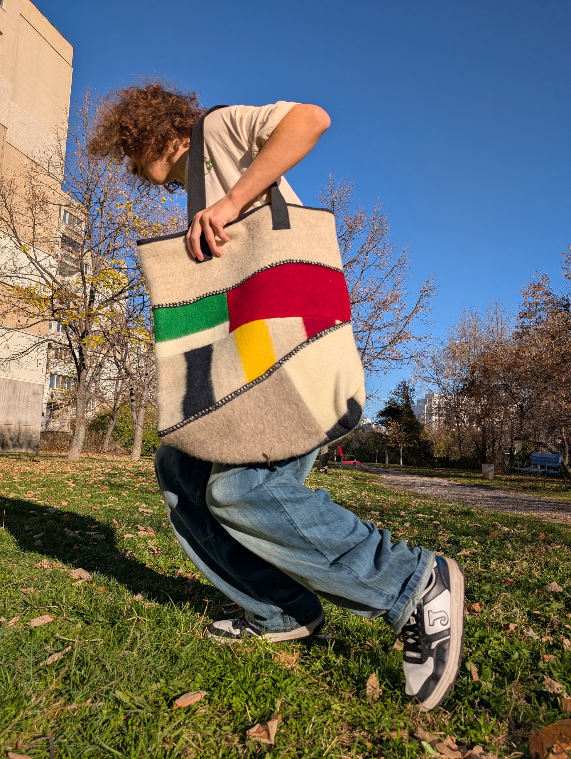 Person holding a loose-fitting street fashion tote bag outdoors on a sunny day