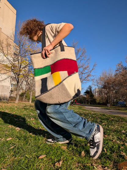 Person holding a loose-fitting street fashion tote bag outdoors on a sunny day