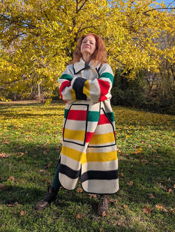 Woman wearing a unisex upcycled wool blanket overcoat with multicolor stripe pattern and a classic collar.