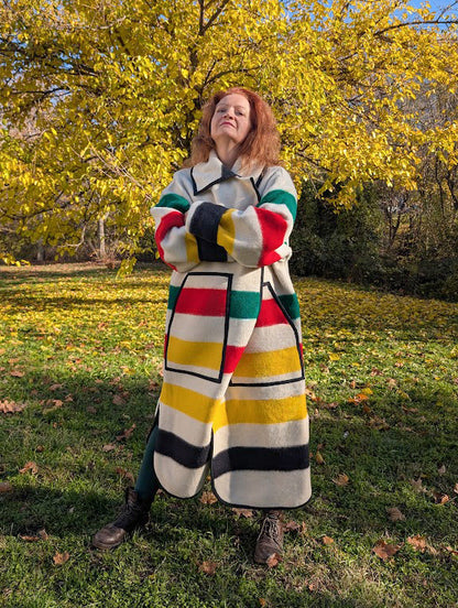 Woman wearing a unisex upcycled wool blanket overcoat with multicolor stripe pattern and a classic collar.