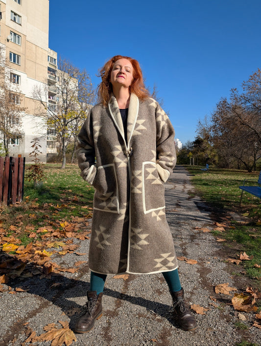 Woman wearing a long robe coat upcycled from undyed pure wool blanket with ethnic diamond geometrical patterns.