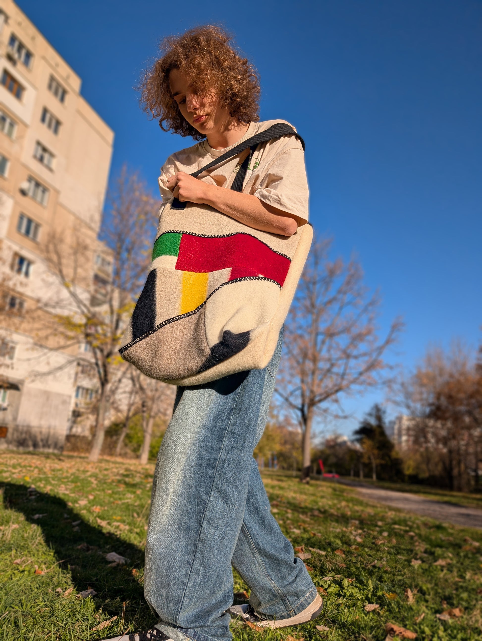 Person holding a functional colorful woolen showlderbag made of woolen blanket cuts.