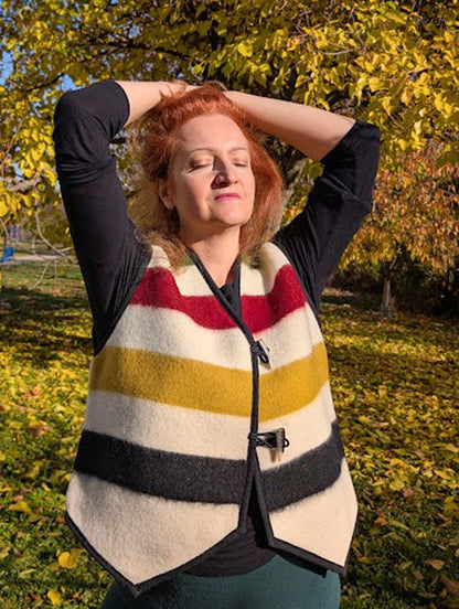Woman wearing a pure wool gilet with iconic colorful stripes, looking very stylish and cool in this statement outerwear.