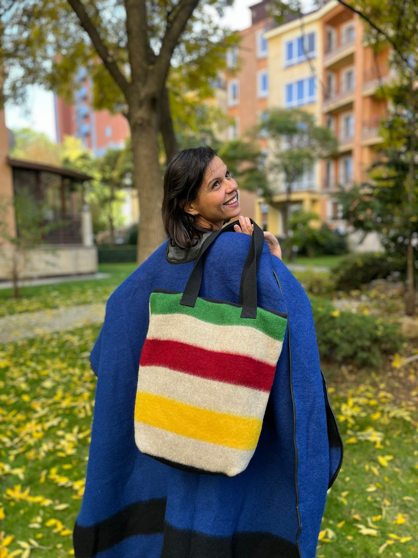 Woman holding a frontier style tote bag upcycled from classic multi stripe blanket leftovers.