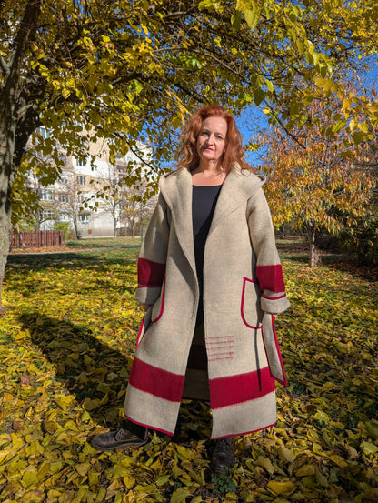 Woman wearing warm upcycled gray wool winter hooded coat, with a red stripe. The model can be worn loose or belted.