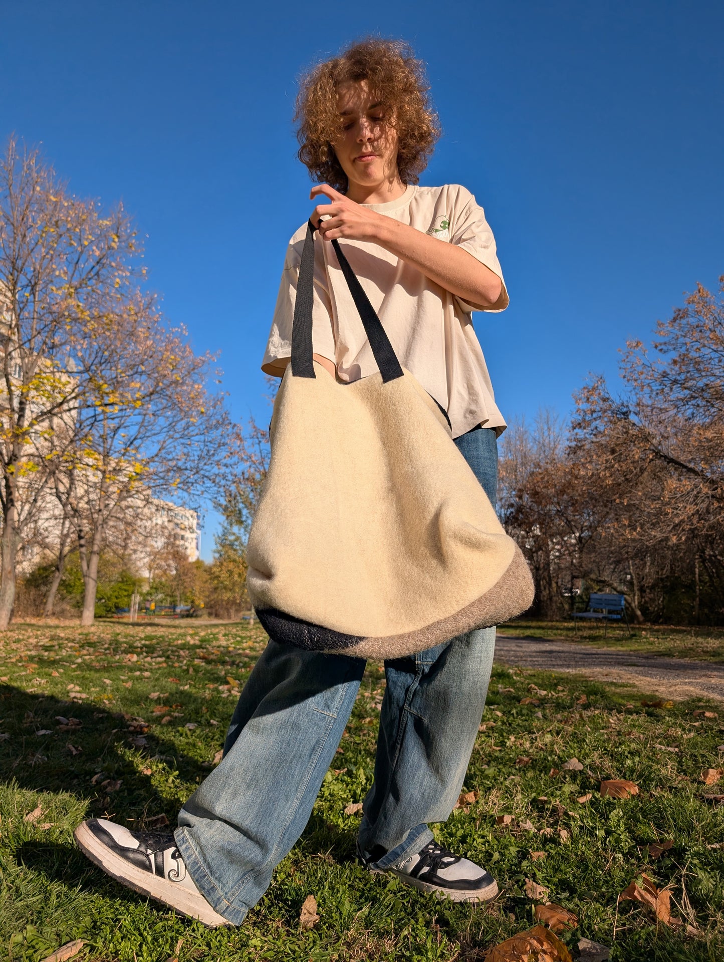 Person showing the plain backside of a functional handmade handbag with original designer patchwork at the front.
